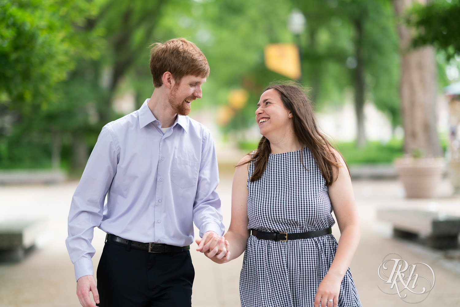 Man and woman walking and laughing during engagement session at University of Minnesota.