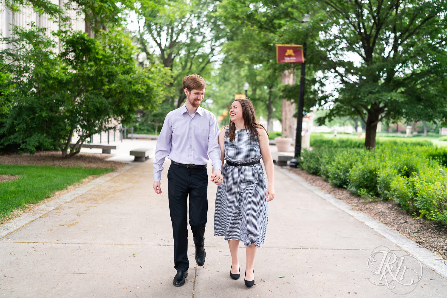 Man and woman walking and laughing during engagement session at University of Minnesota.