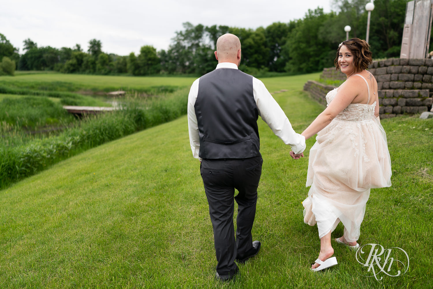 Bride and groom walking in grass at Barn at Crocker's Creek in Faribault, Minnesota.