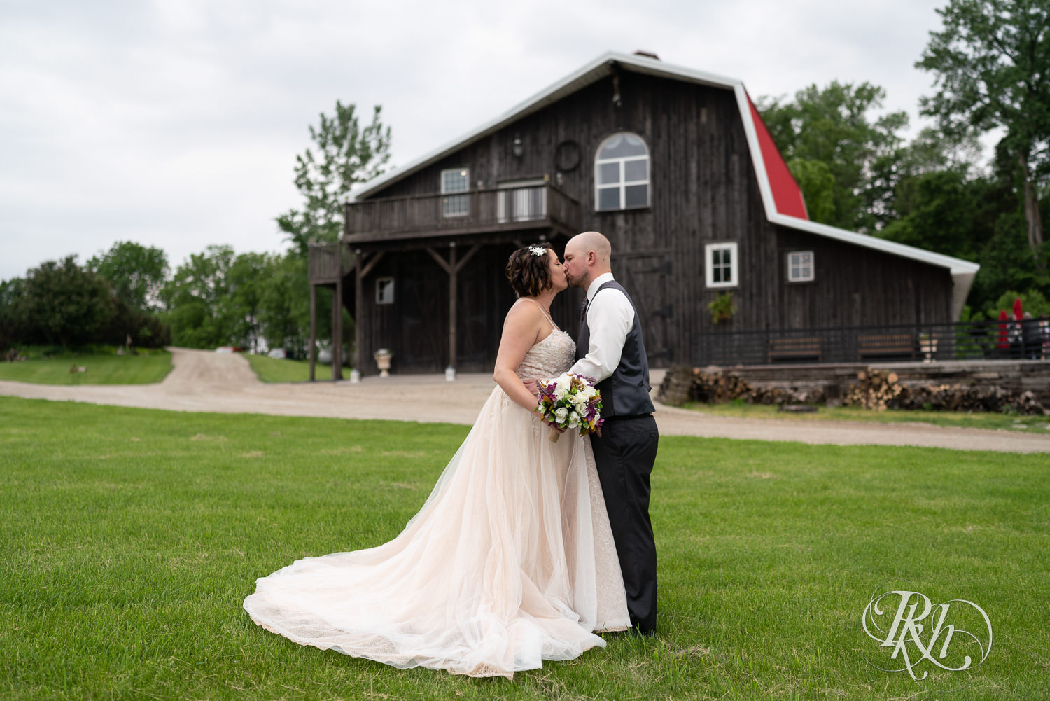 couple kissing in front of barn wedding venue