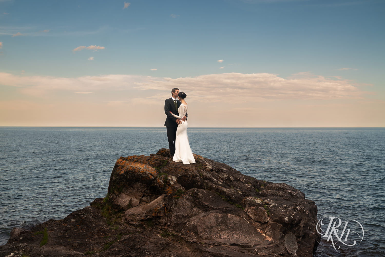 Bride and groom kissing on a cliff in front of Lake Superior at sunset in Tofte, Minnesota.