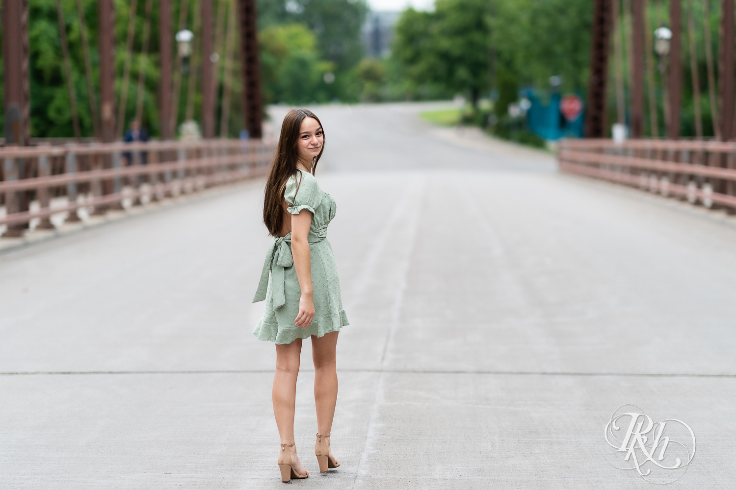 Lexi walking on a bridge a green dress for senior photography in Minneapolis, Minnesota.