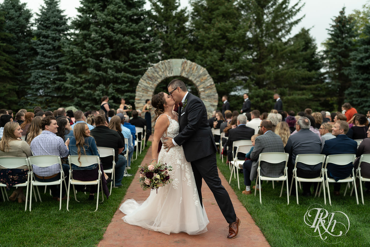 Bride and groom kiss after ceremony on rainy day at Glenhaven Events in Farmington, Minnesota.