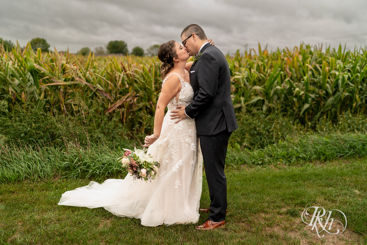 Bride and groom kissing each other in front of cornfield at Glenhaven Events in Farmington, Minnesota.