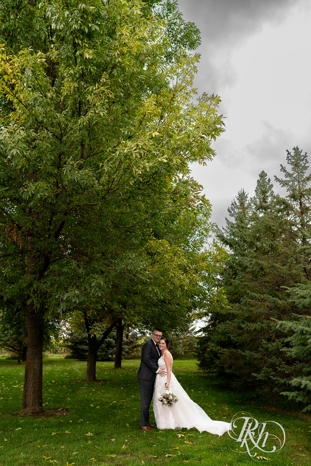 Bride and groom together on rainy day at Glenhaven Events in Farmington, Minnesota under a tree.