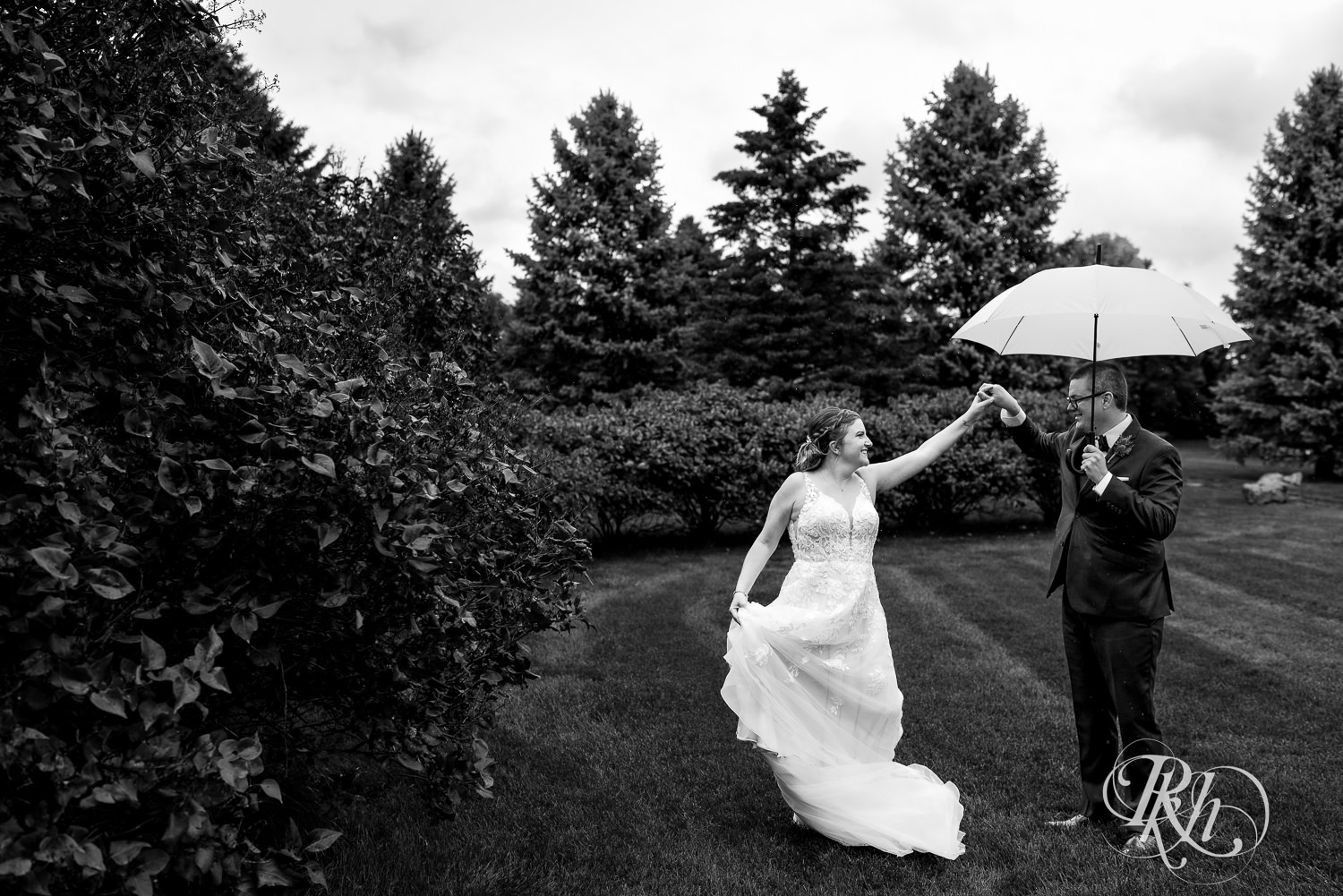 Bride and groom dancing under yellow umbrella on rainy day at Glenhaven Events in Farmington, Minnesota.