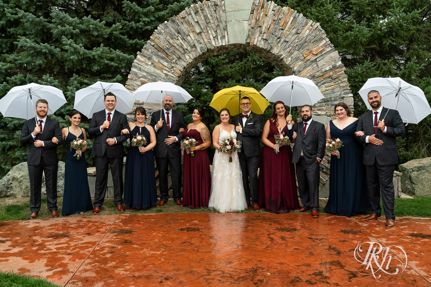 Wedding party with umbrellas on rainy day at Glenhaven Events in Farmington, Minnesota.