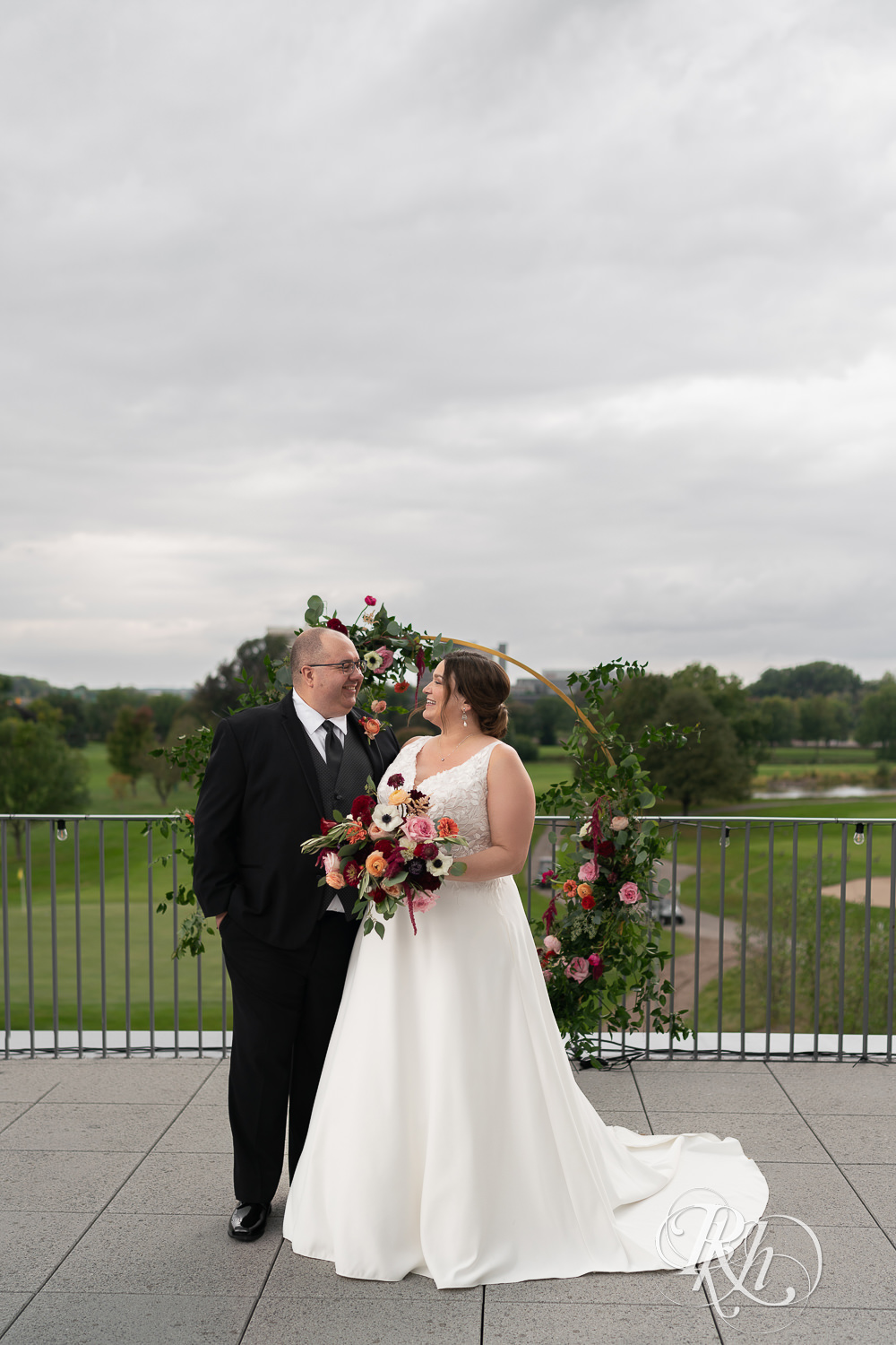 Wedding couple laughing and facing each other at Brookview Golf Course in Golden Valley, Minnesota.