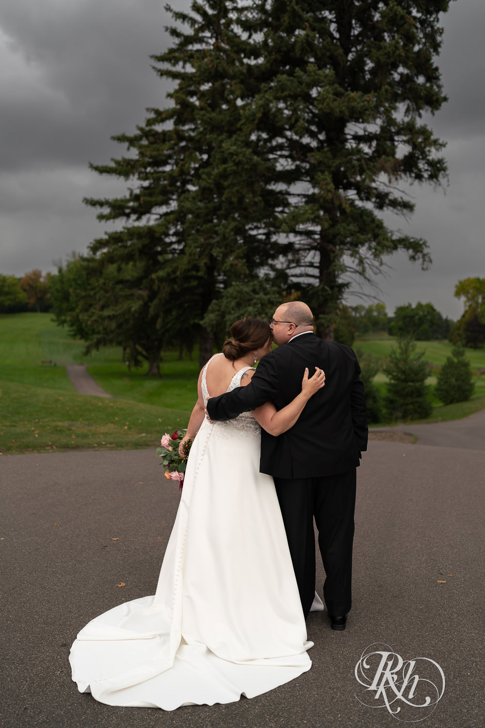Groom kissing bride's head at Brookview Golf Course in Golden Valley, Minnesota.