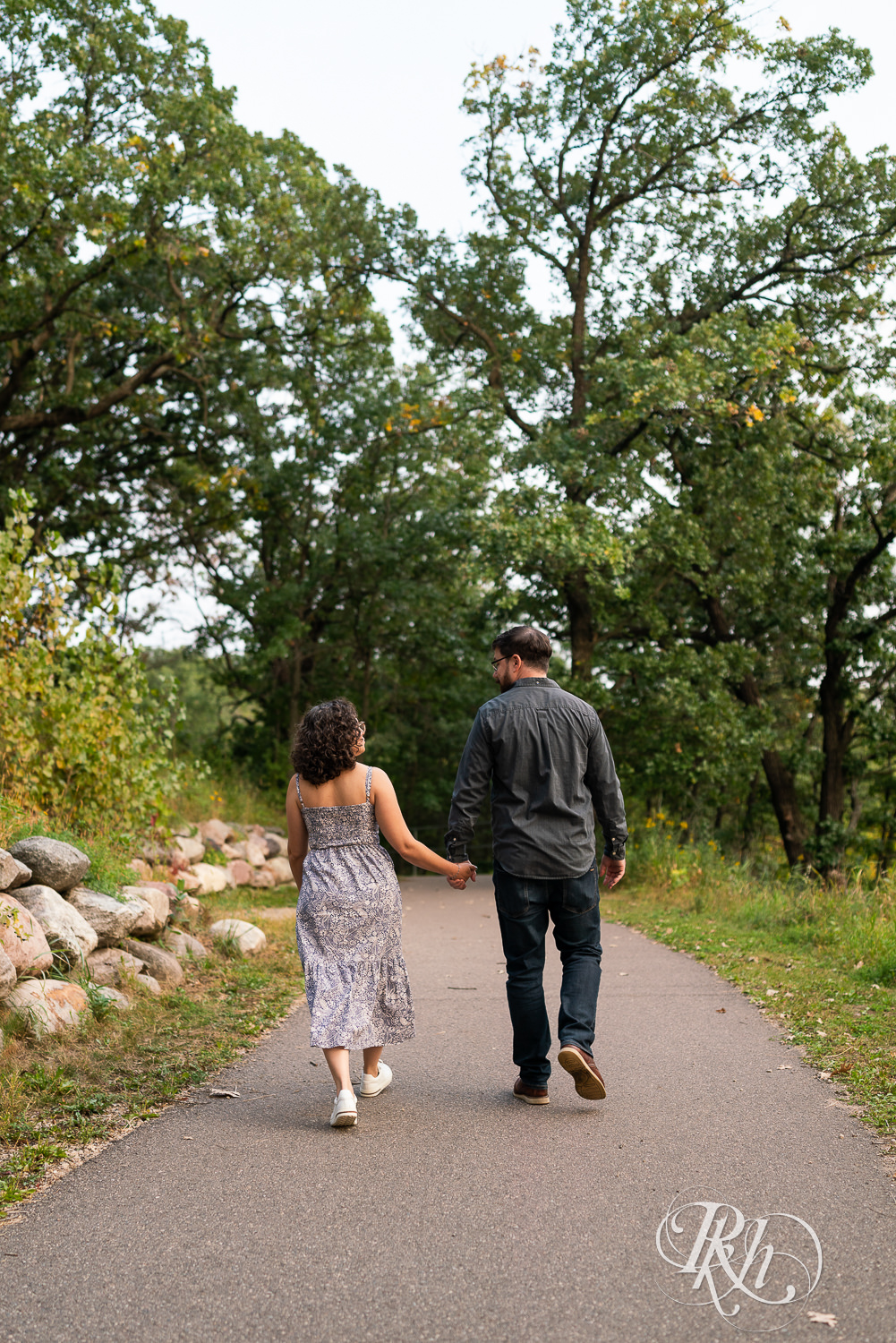 Man and woman walking down path holding hands.