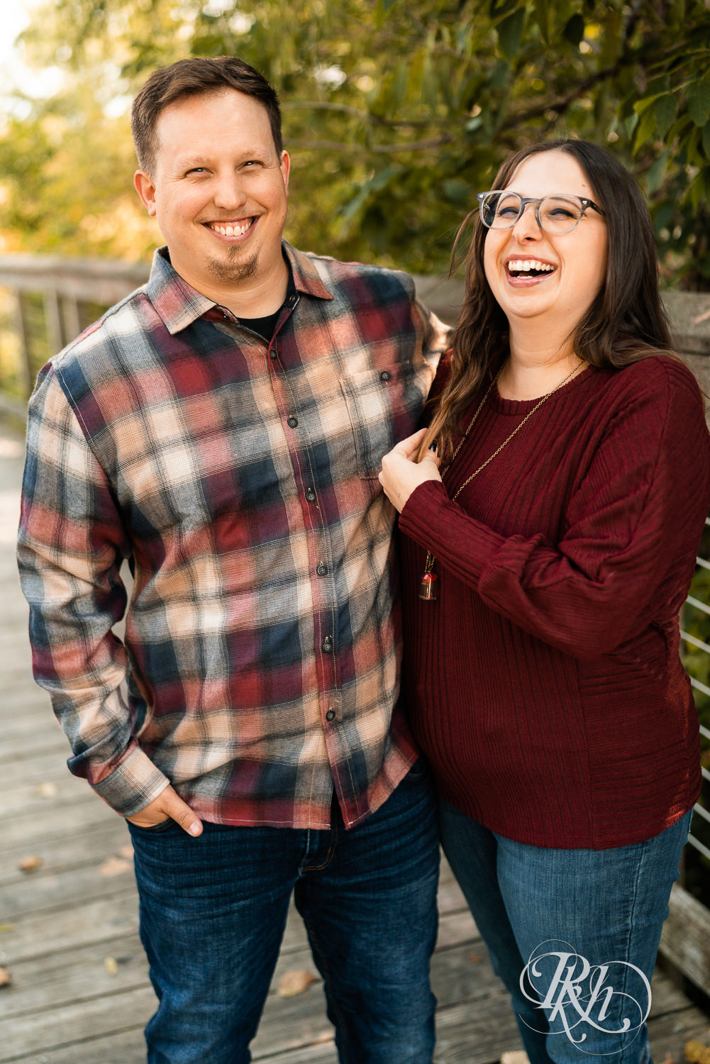 Couple laughing on bridge in Eagan, Minnesota during their fall engagement photography.