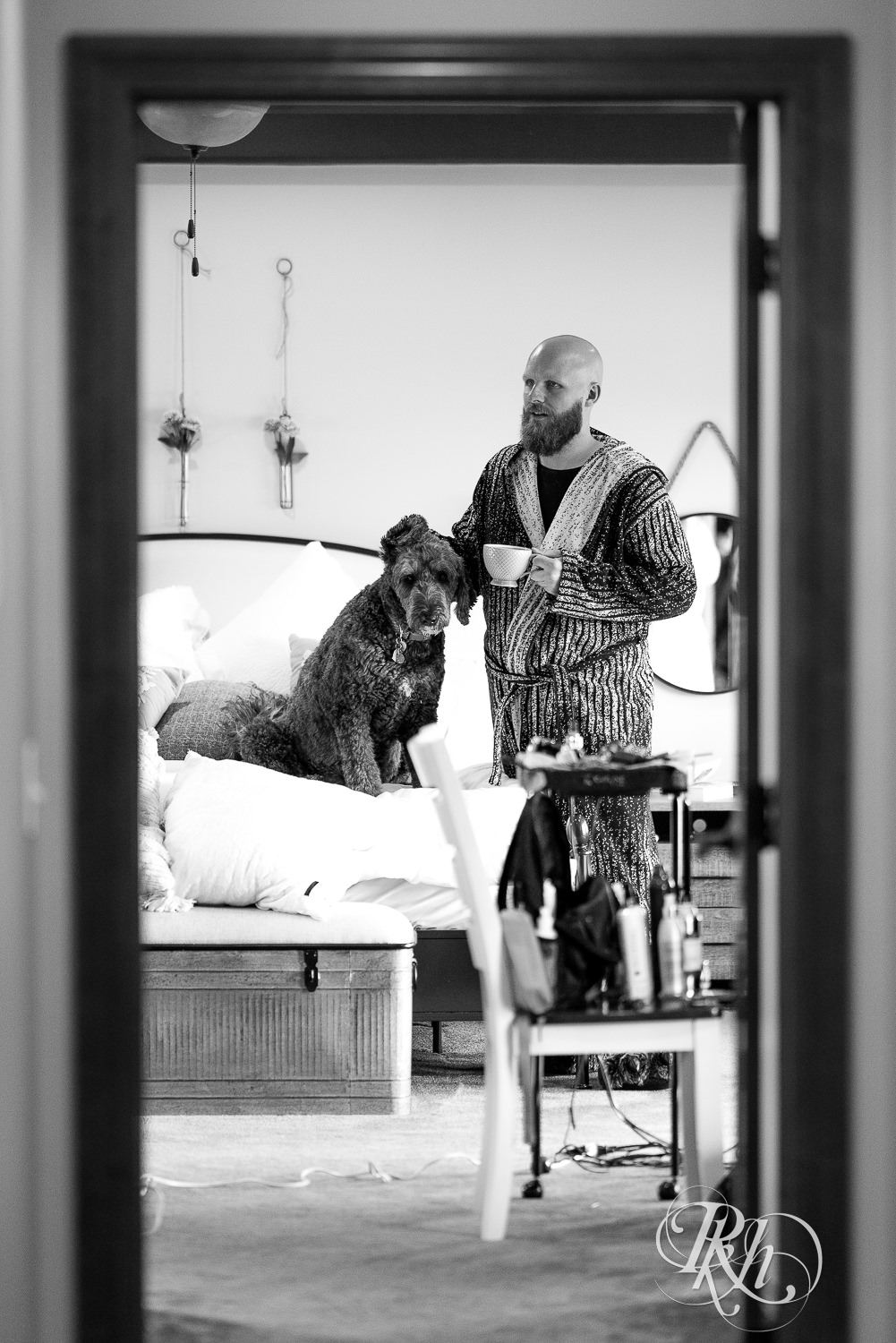 Groom petting dog while getting ready for wedding and drinking coffee.