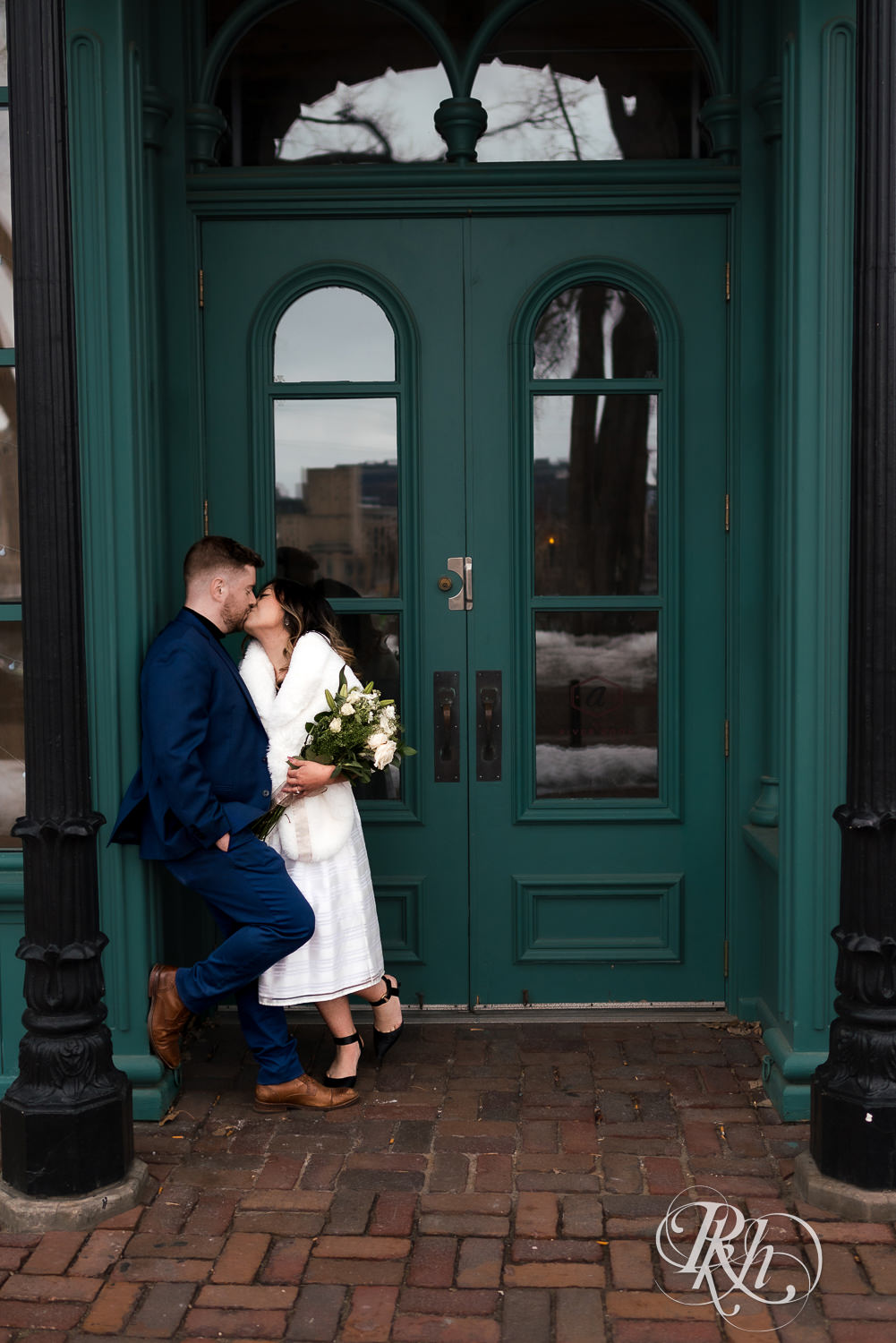 Man and Hmong woman kiss in front of door in Saint Anthony Main in Minneapolis, Minnesota.