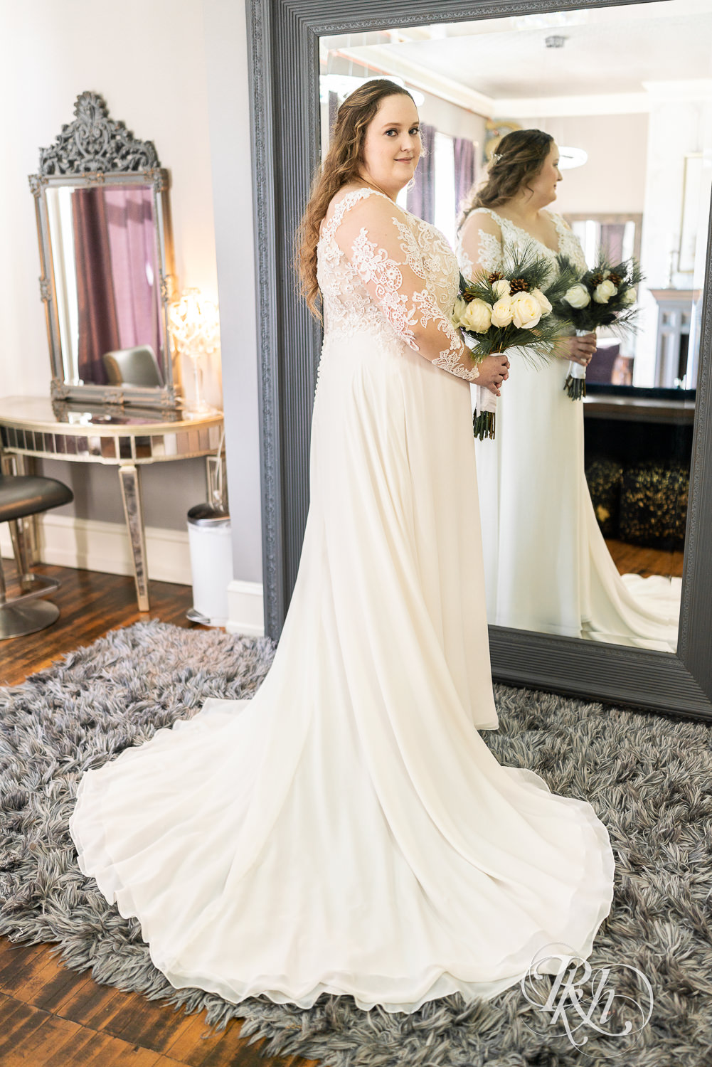 Bride standing in front of mirror holding flower at Semple Mansion in Minneapolis, Minnesota.