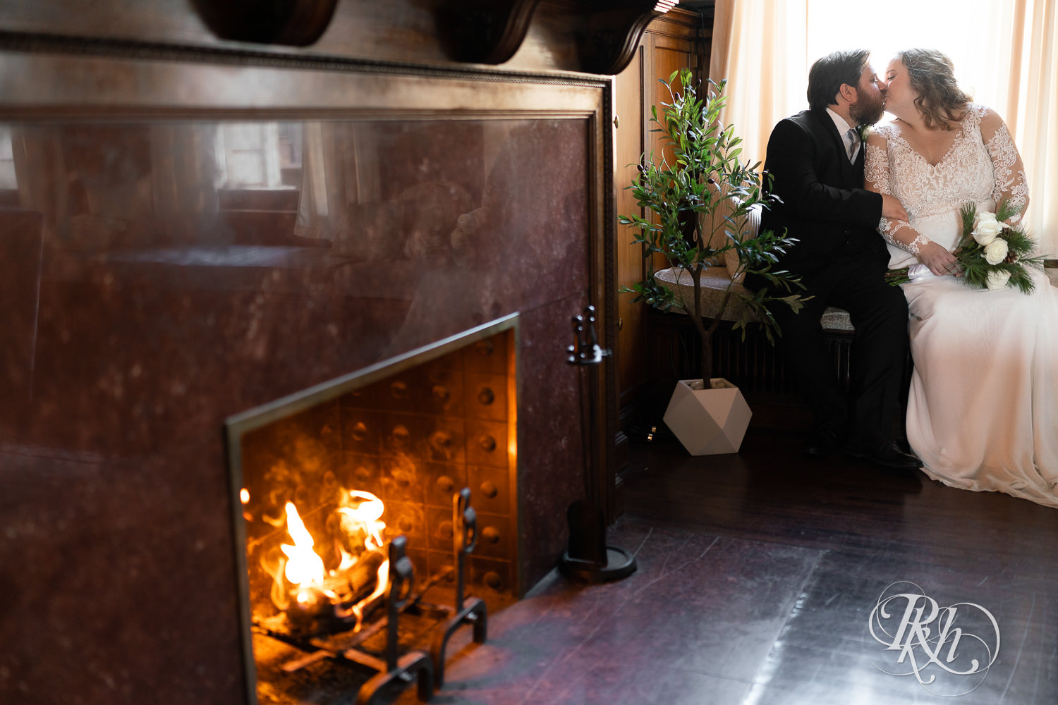 Bride and groom kissing in front of fireplace at Semple Mansion in Minneapolis, Minnesota.