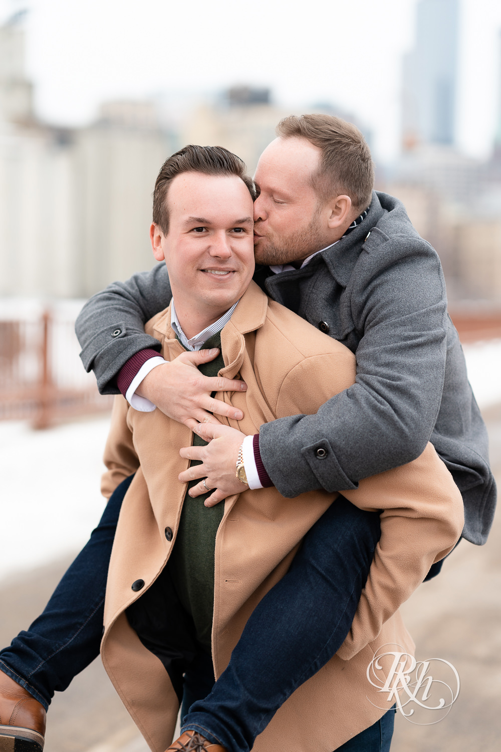 Gay men do a piggy back ride on the Stone Arch Bridge during the winter in Minneapolis, Minnesota.