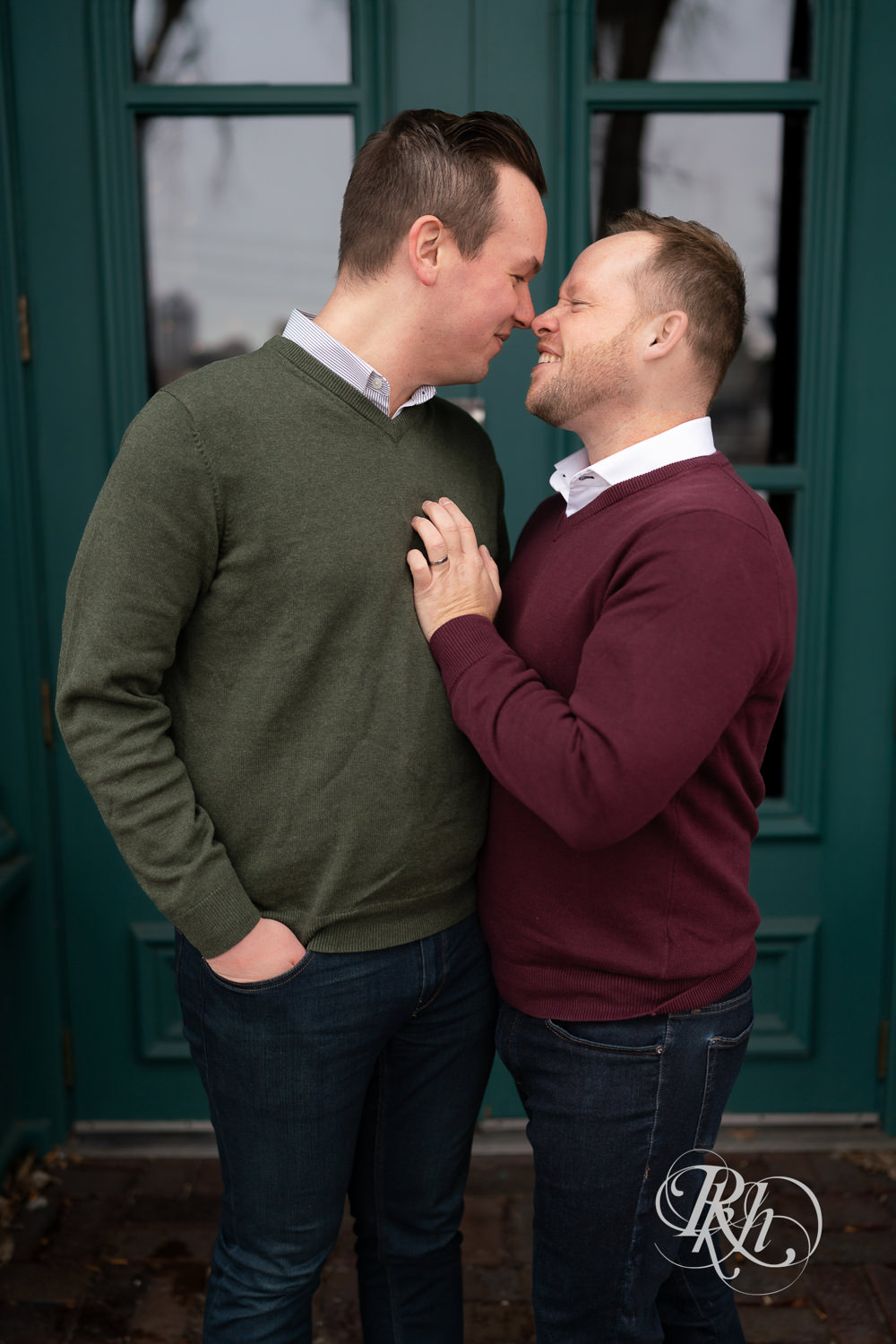 Gay men kiss in front of blue doors during the winter in Minneapolis, Minnesota.
