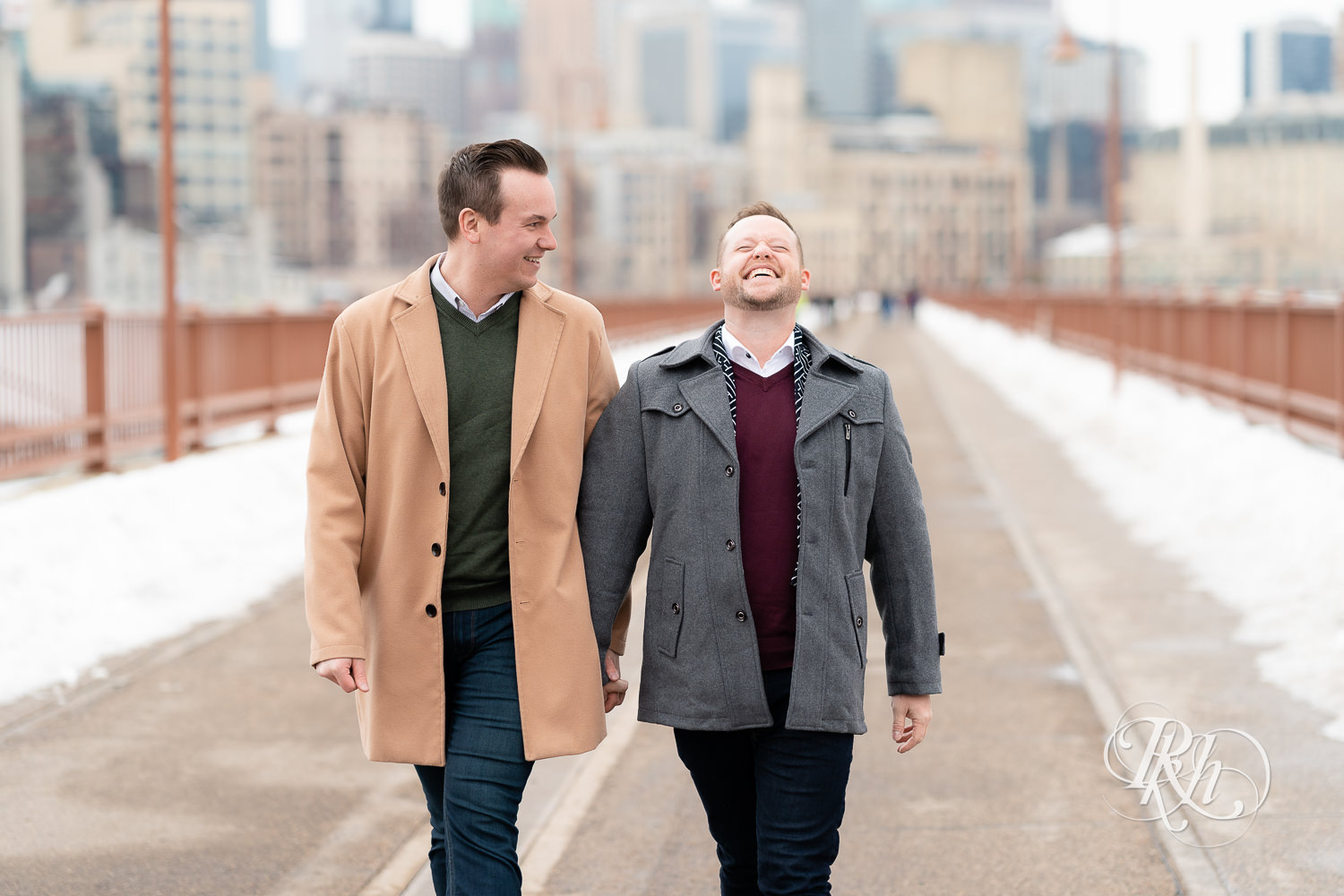 Gay men laugh on the Stone Arch Bridge during the winter in Minneapolis, Minnesota.