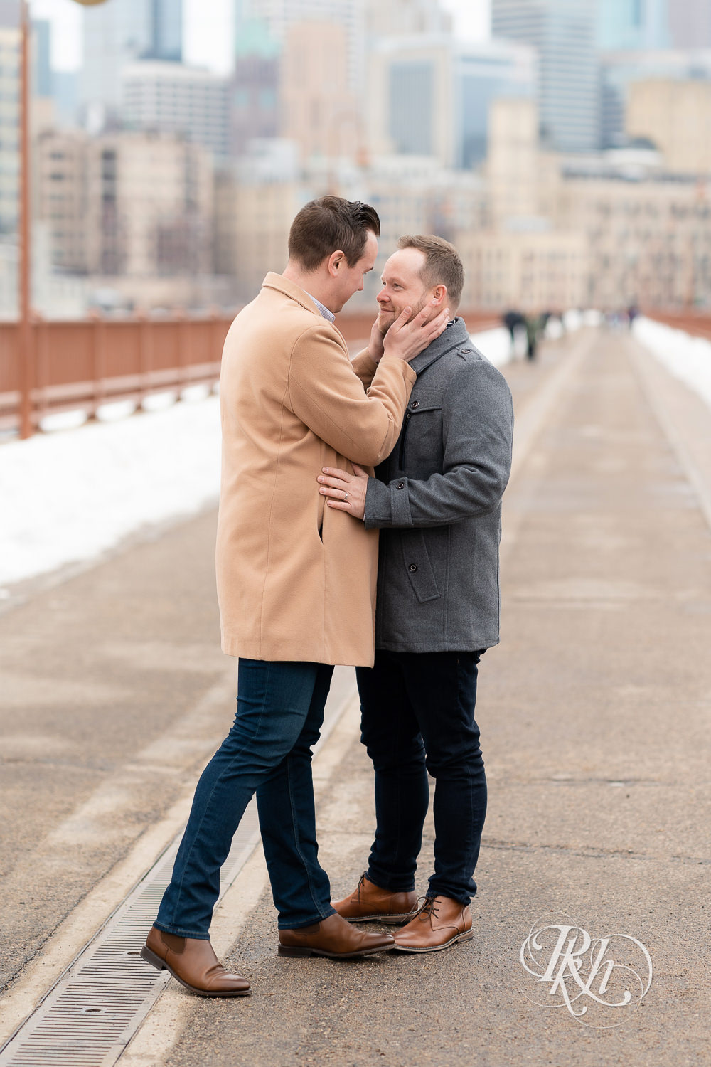 Gay men smile on the Stone Arch Bridge during the winter in Minneapolis, Minnesota.