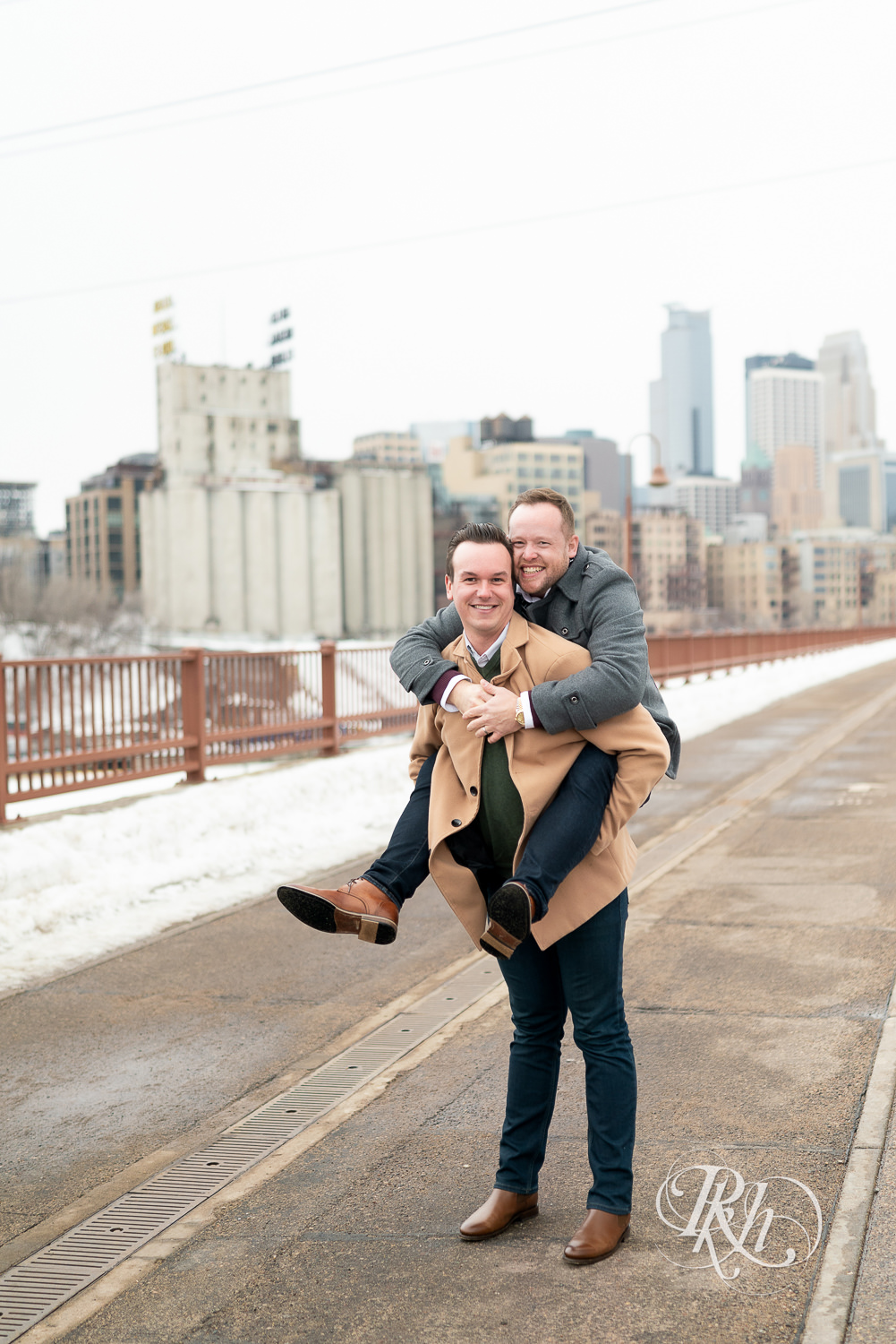 Gay men do a piggy back ride on the Stone Arch Bridge during the winter in Minneapolis, Minnesota.