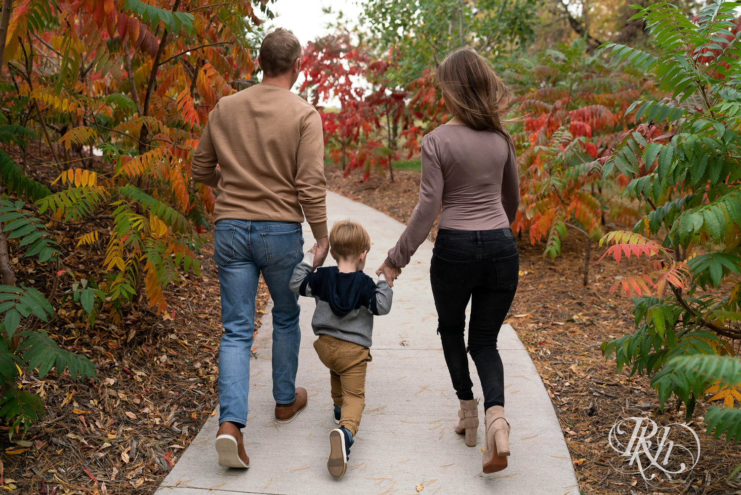 Minnesota fall family photography of little boy walking with parents at Whitetail Woods in Farmington, Minnesota.