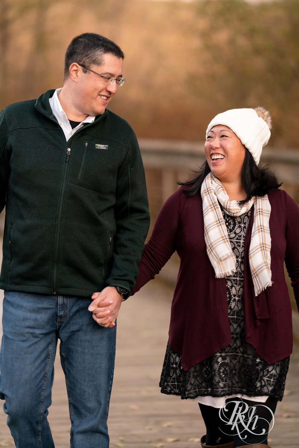 Man and Korean woman walk on bridge laughing at Lebanon Hills Regional Park in Eagan, Minnesota.