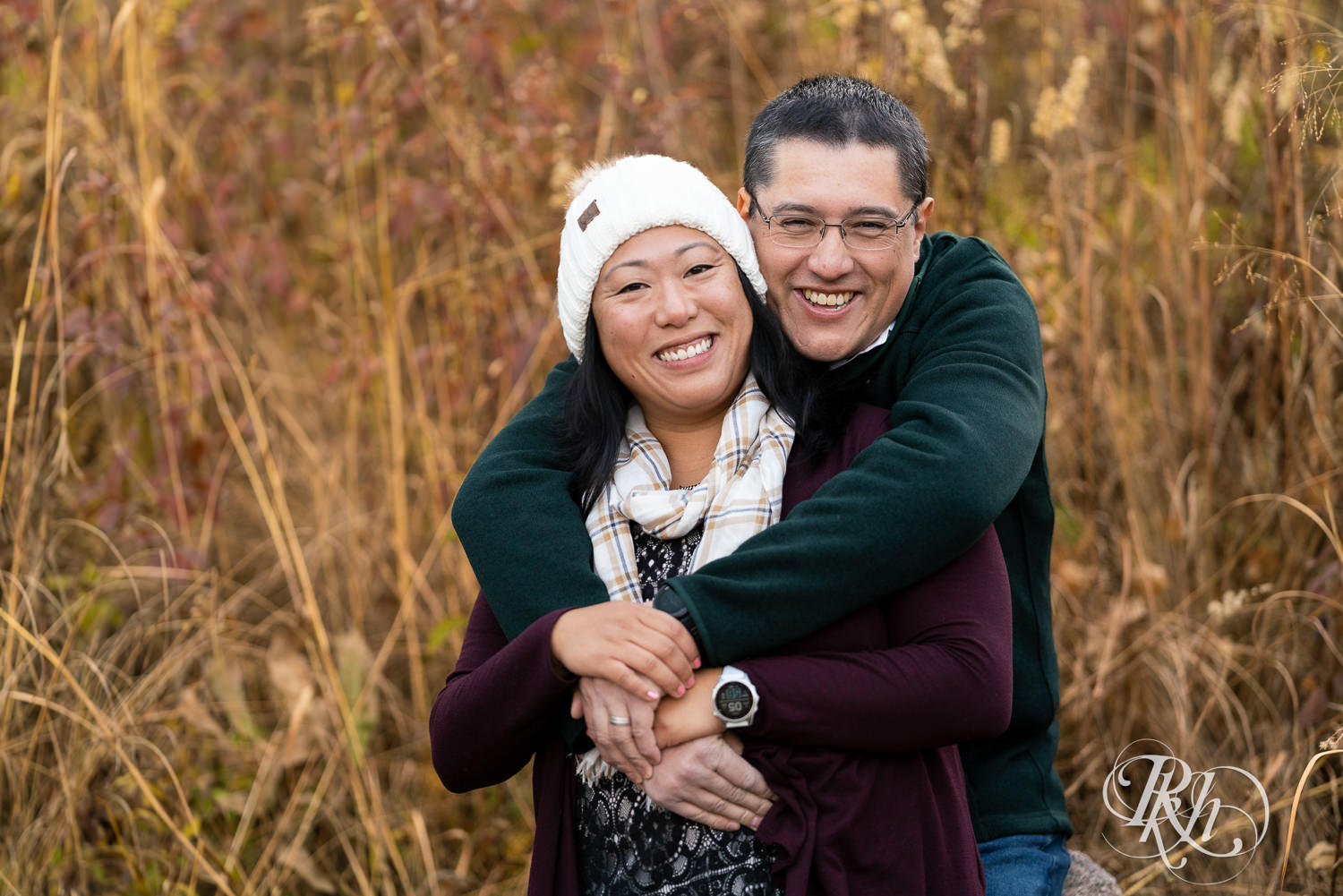 Man and Korean woman smile in fall colors at Lebanon Hills Regional Park in Eagan, Minnesota.