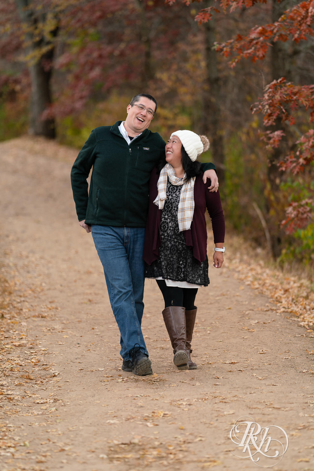Man and Korean woman walk down trail laughing in fall colors at Lebanon Hills Regional Park in Eagan, Minnesota.