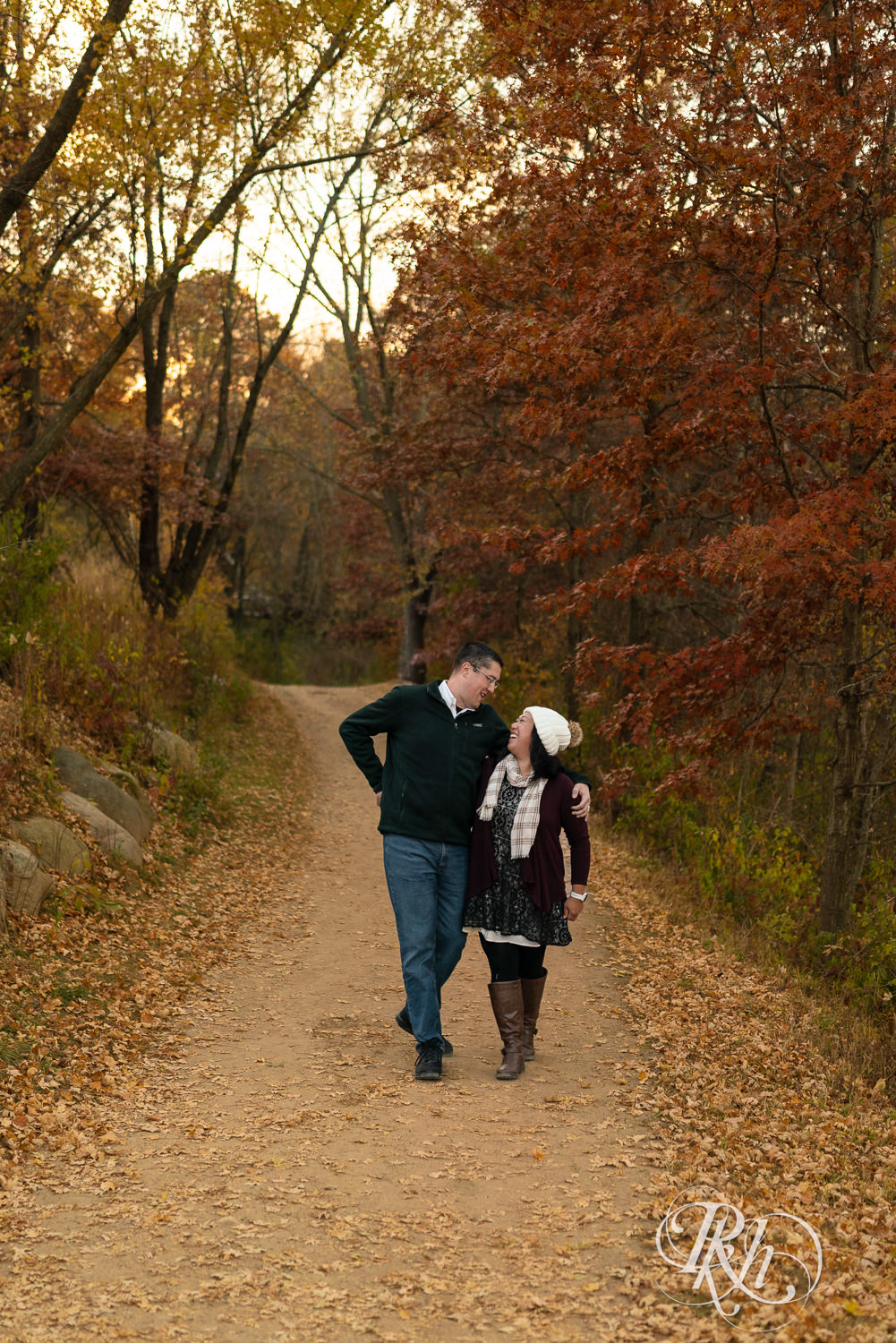 Man and Korean woman walk down trail laughing in fall colors at Lebanon Hills Regional Park in Eagan, Minnesota.
