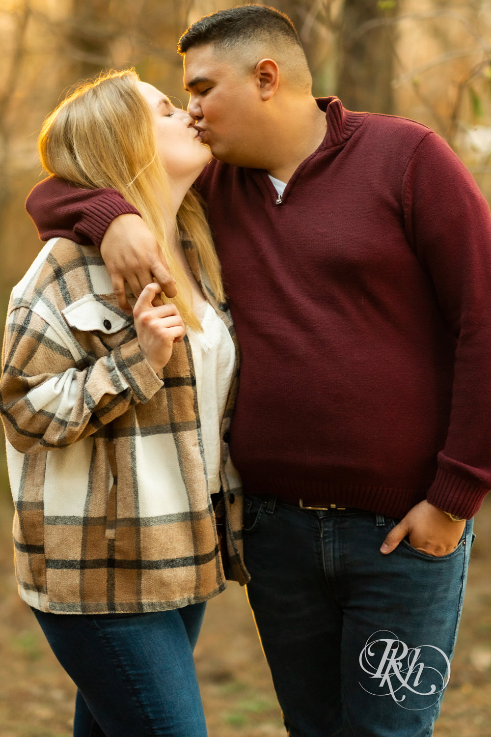 Filipino man and woman in flannel and jeans kiss during sunset at Lebanon Hills in Eagan, Minnesota.