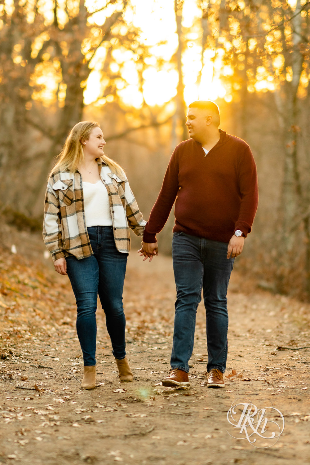 Filipino man and woman in flannel and jeans and kiss while walking towards sunset at Lebanon Hills in Eagan, Minnesota.