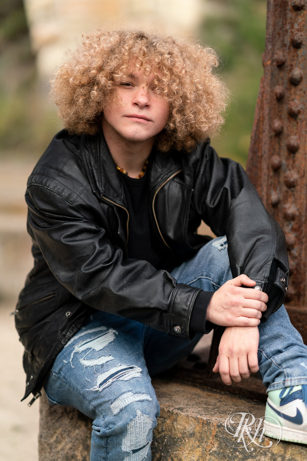 Senior boy playing dressed in leather and jeans in downtown Minneapolis senior photography session.