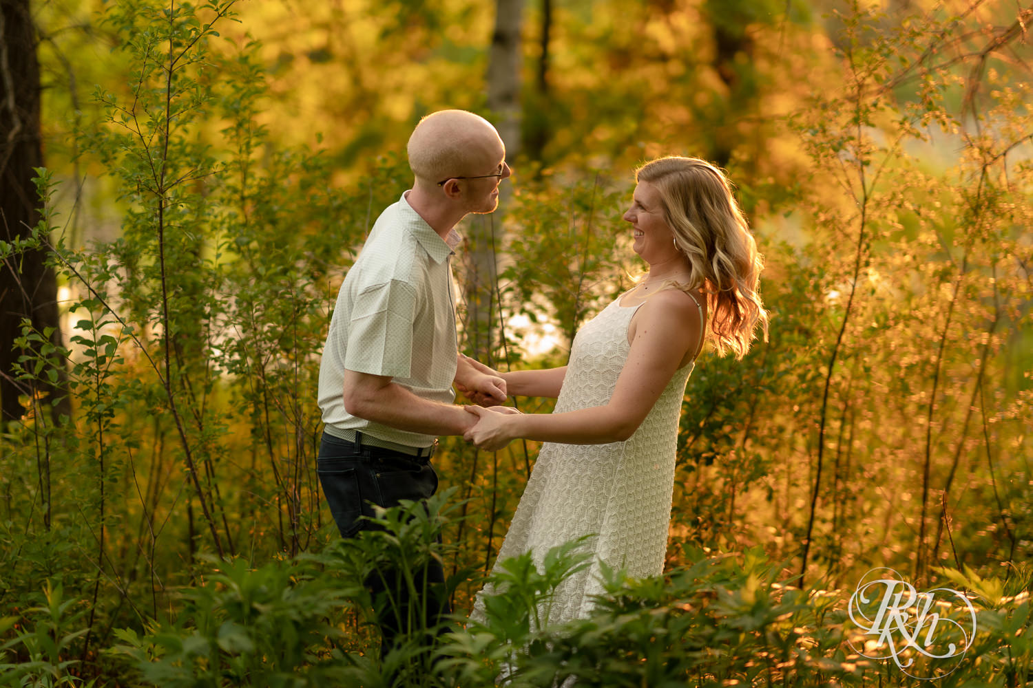 Man in white shirt and blonde woman in white dress and denim smile at sunset in Lebanon Hills Regional Park in Eagan, Minnesota.