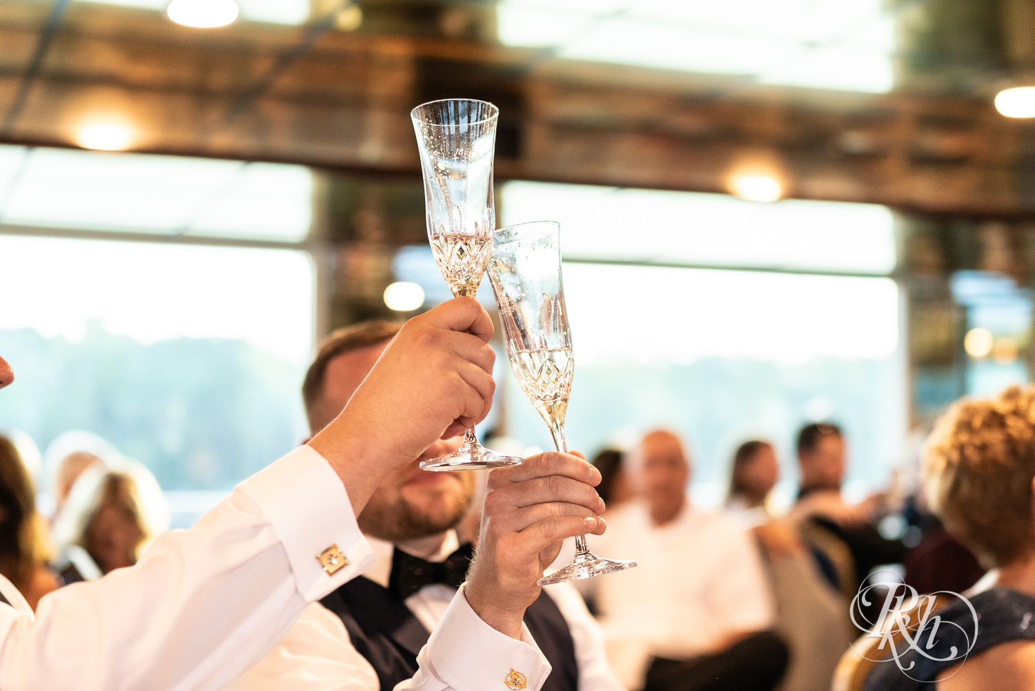 Grooms toast during speeches on the Majestic Star by Stillwater River Boats in Stillwater, Minnesota.