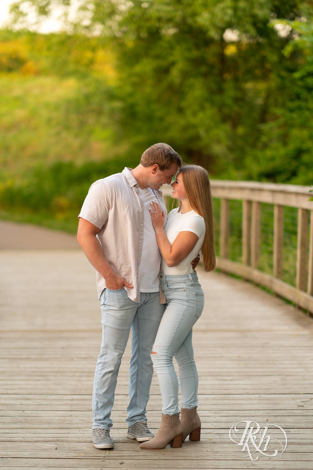 Man and woman in jeans laugh on smile during golden hour engagement photography in Eagan, Minnesota.