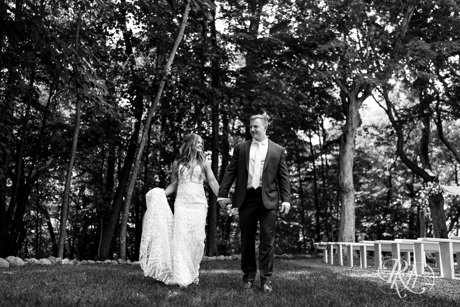 Bride and groom walk in the grass on wedding day at Ahavah Cottage in Elysian, Minnesota.