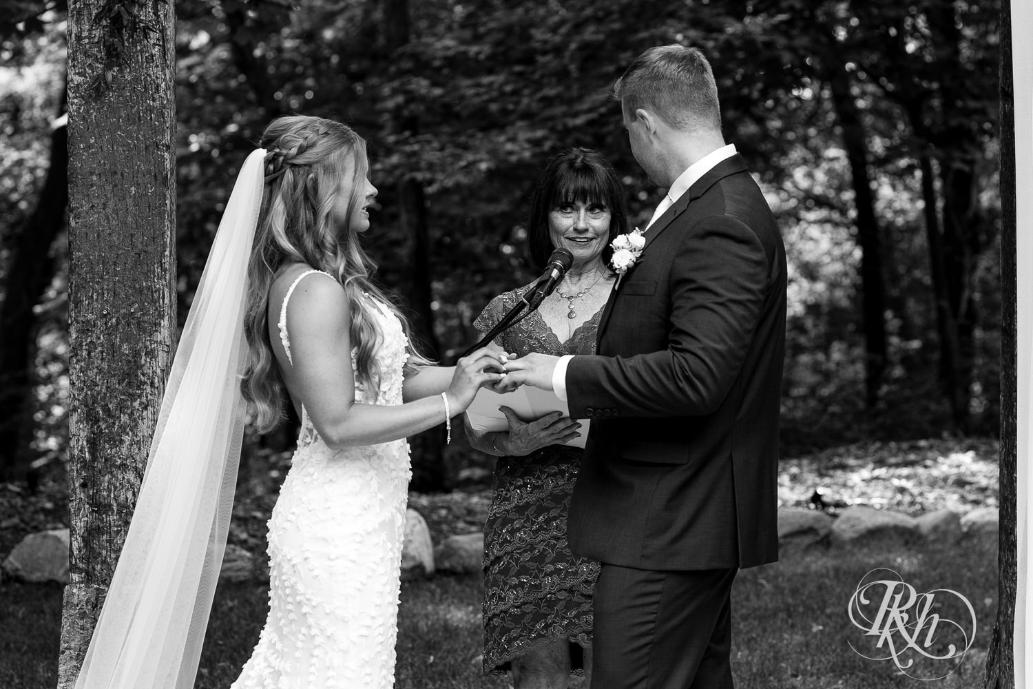 Bride and groom exchange rings during wedding ceremony on wedding day at Ahavah Cottage in Elysian, Minnesota.