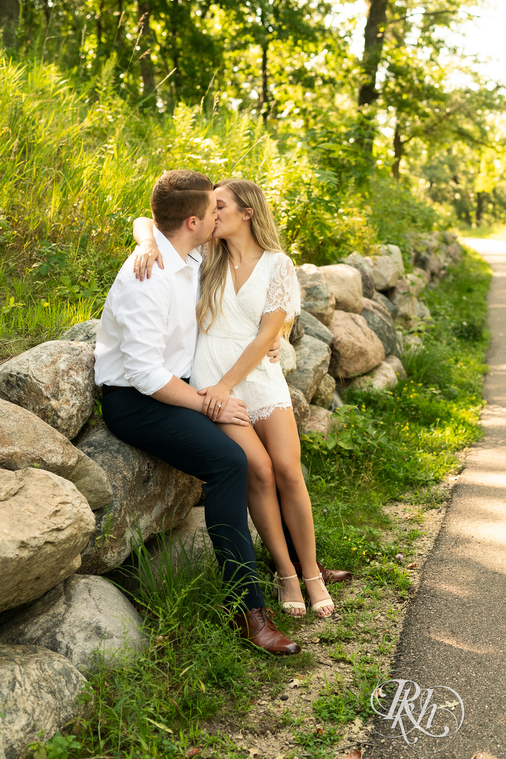 Man and woman dressed in white kiss during summer engagement photography in Minnesota.
