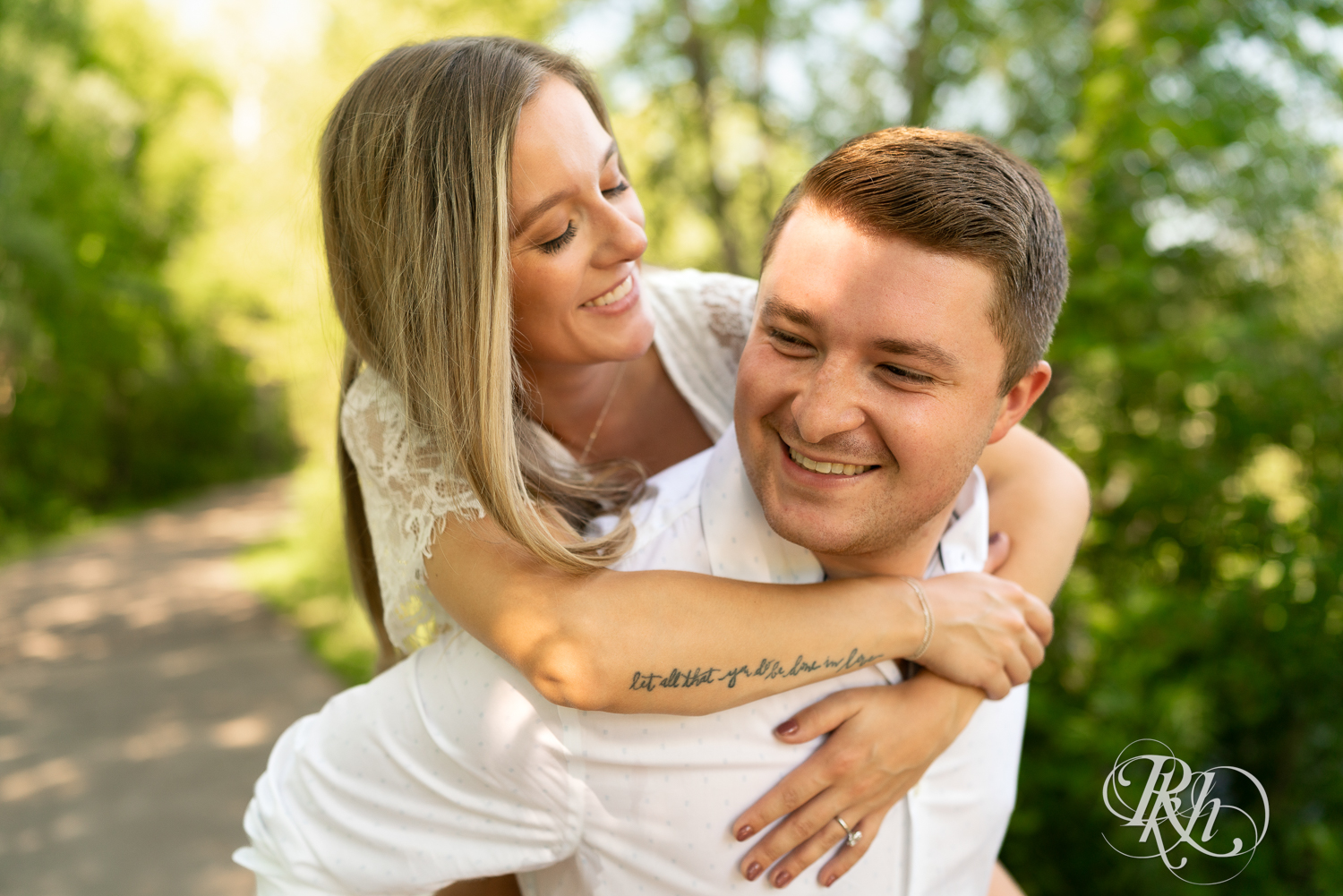 Man gives woman a piggyback ride during summer engagement photography in Minnesota.