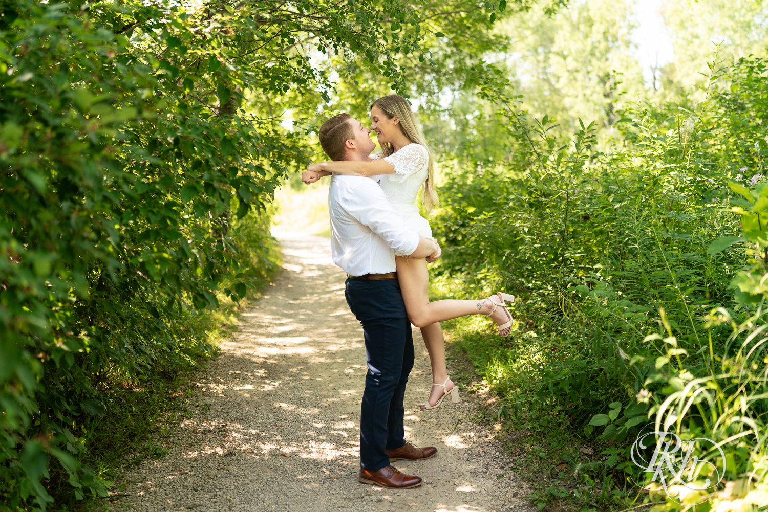 Man lifts woman during summer engagement photography in Minnesota.