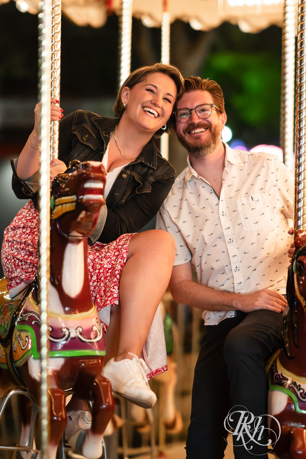 Man and woman ride carousel during their engagement photography at the Minnesota State Fair. 