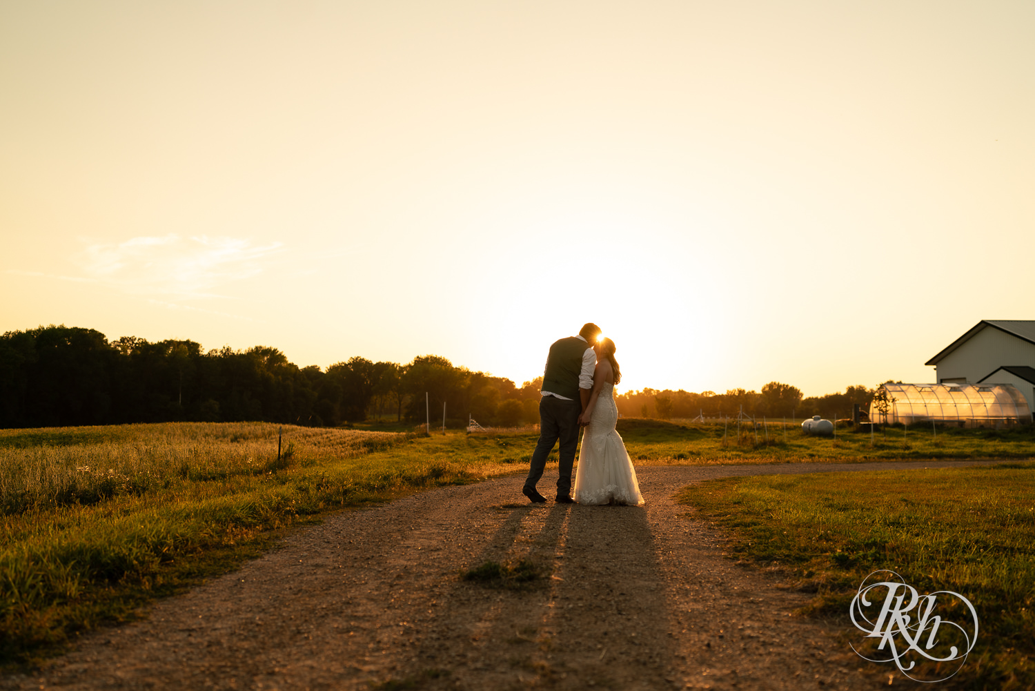 Bride and groom kiss at sunset on wedding day at Cottage Farmhouse in Glencoe, Minnesota.