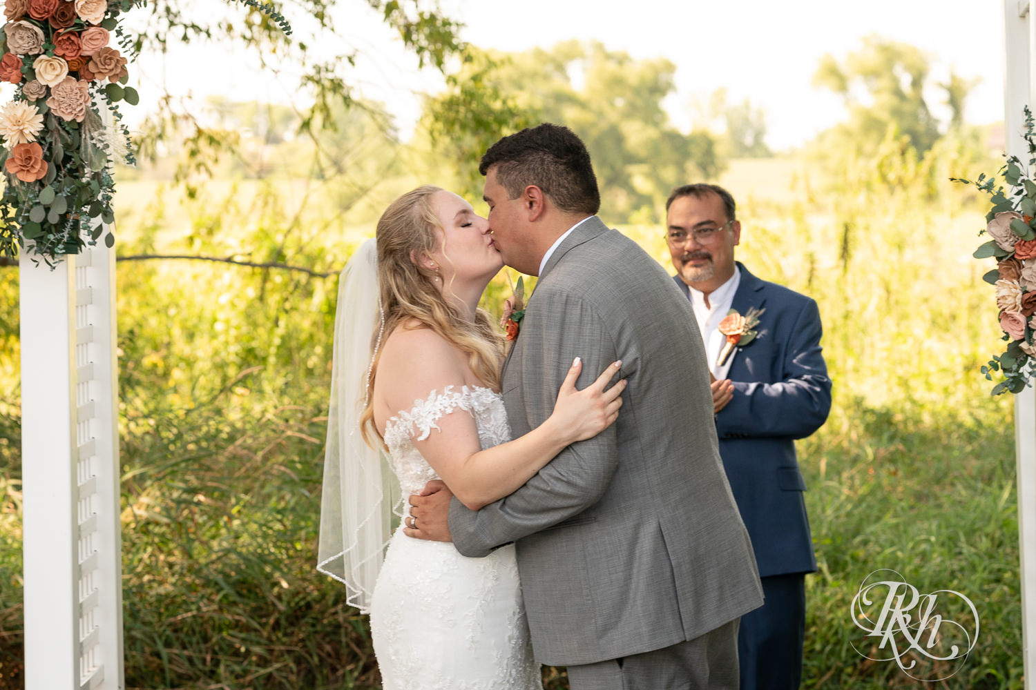 Bride and groom kiss during summer wedding ceremony at Cottage Farmhouse in Glencoe, Minnesota.