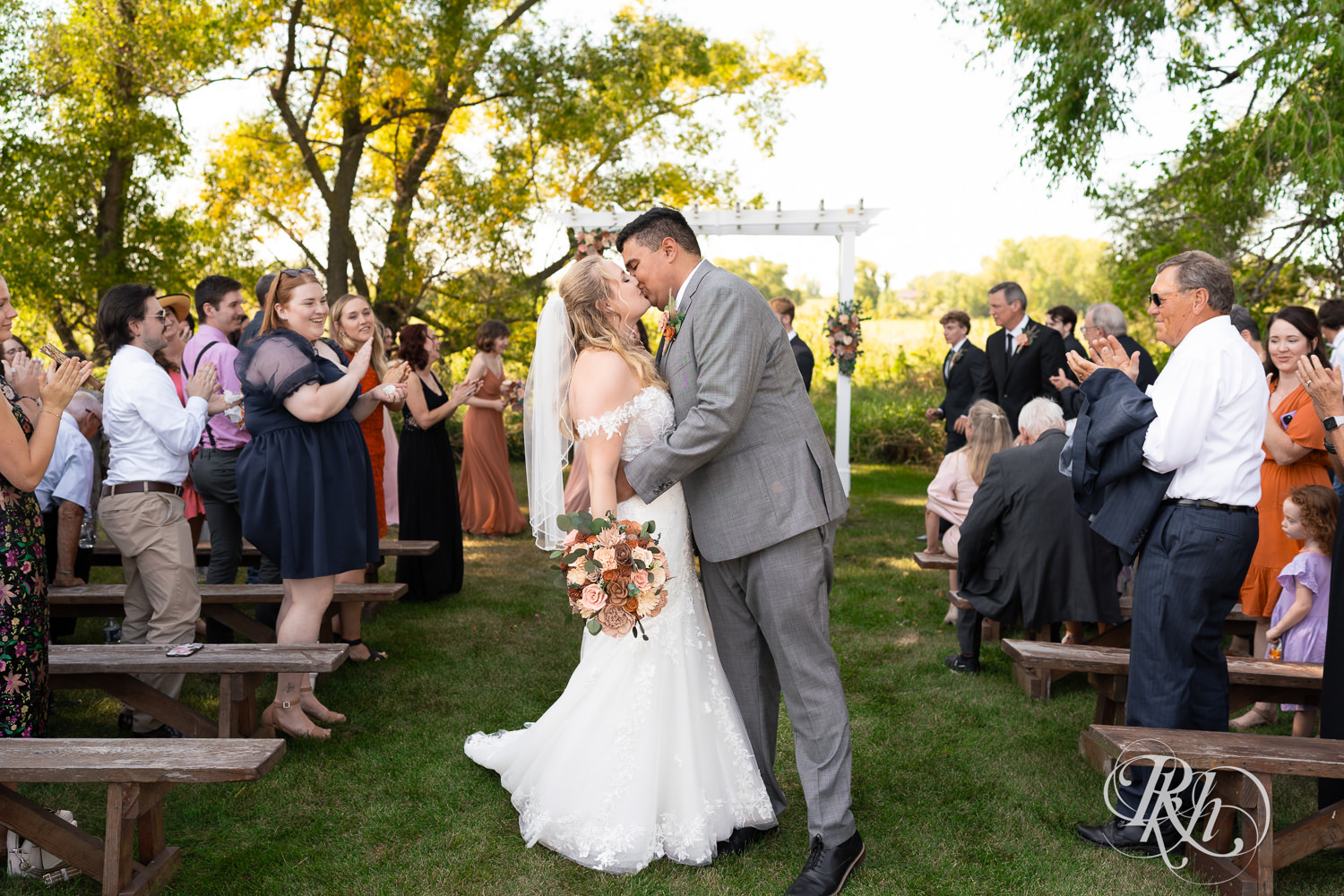 Bride and groom kiss after summer wedding ceremony at Cottage Farmhouse in Glencoe, Minnesota.
