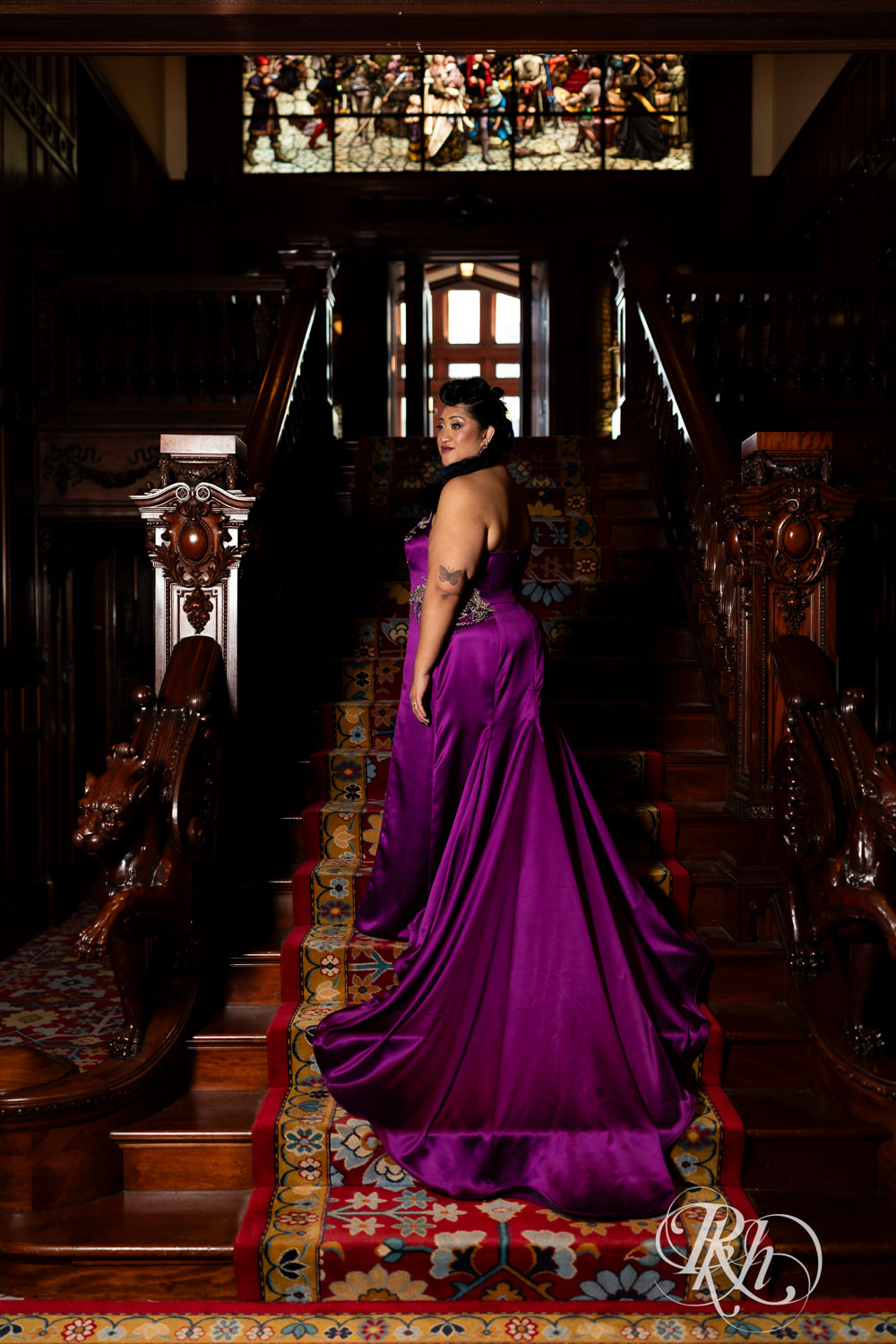 Filipino bride with mohawk dressed in purple wedding dress stands on stairs at American Swedish Institute in Minnesota.