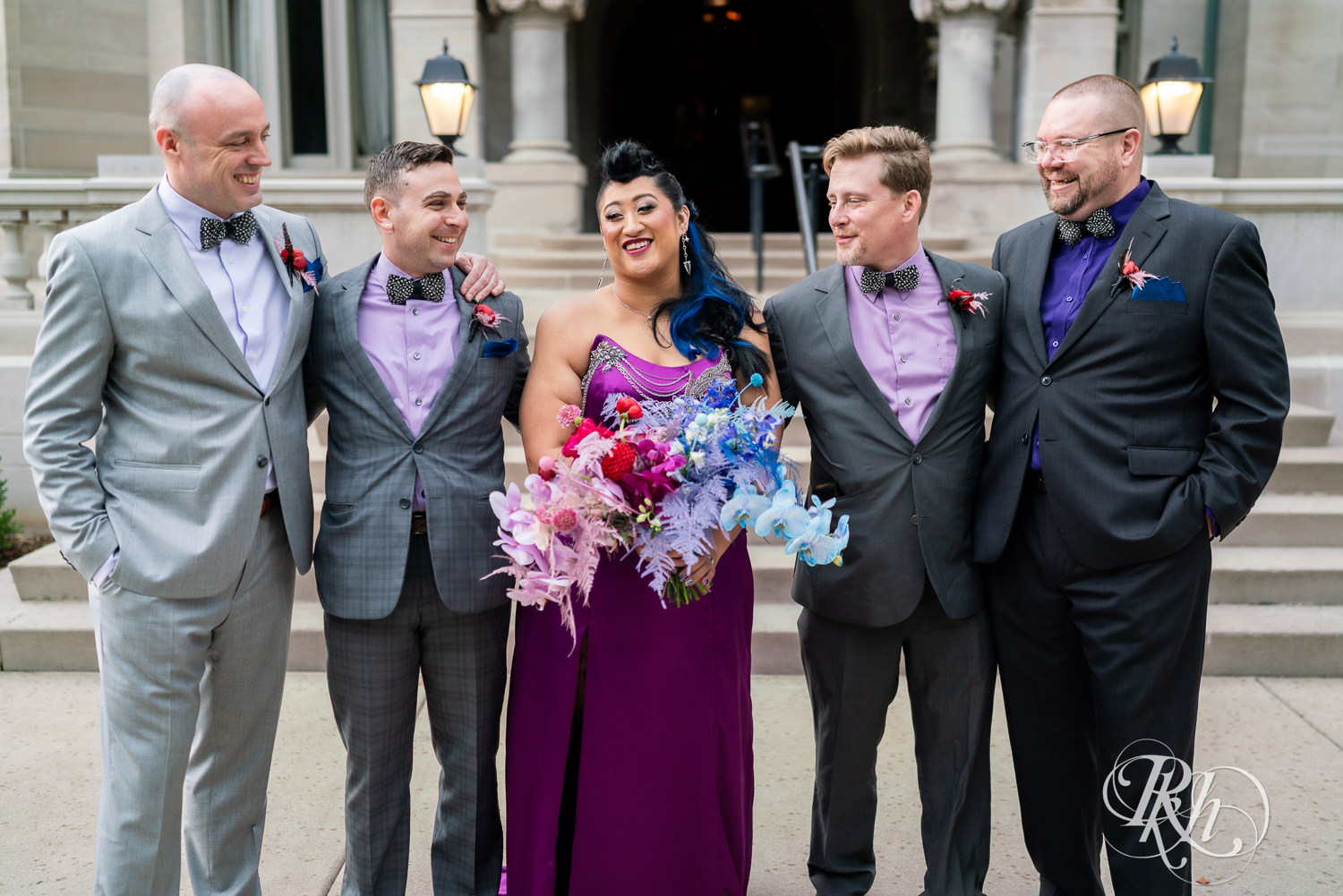 Filipino bride with mohawk dressed in purple wedding dress smiles with the wedding party in front of the American Swedish Institute. 