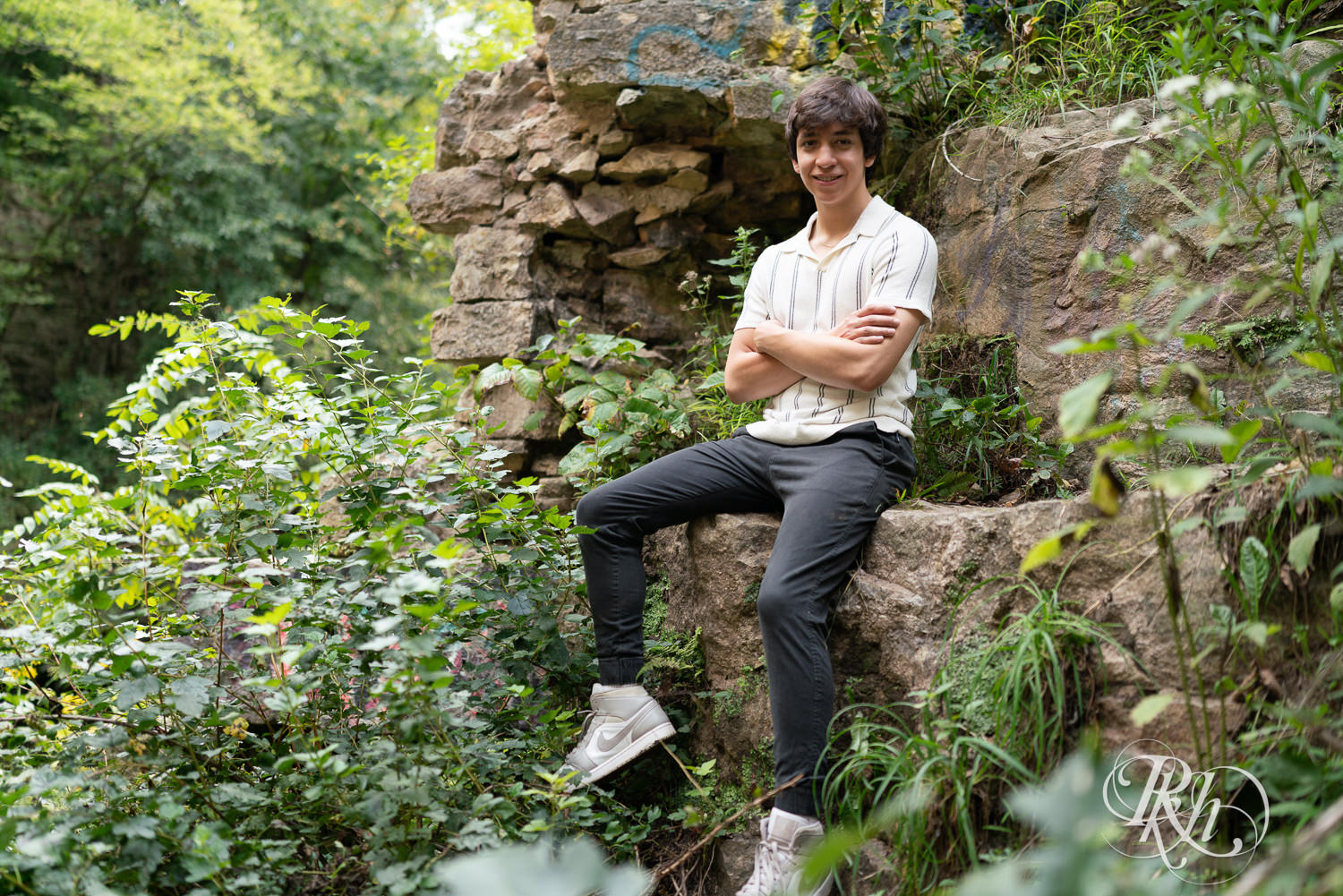 High school senior boy smiles during senior photography at Old Mill Park in Hastings, Minnesota.