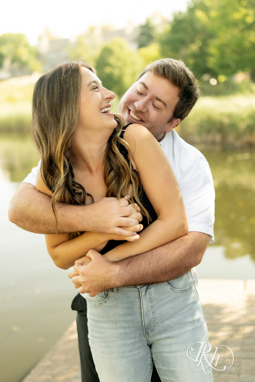 Man and woman laugh during engagement photography at Centennial Lakes Park in Edina, Minnesota.