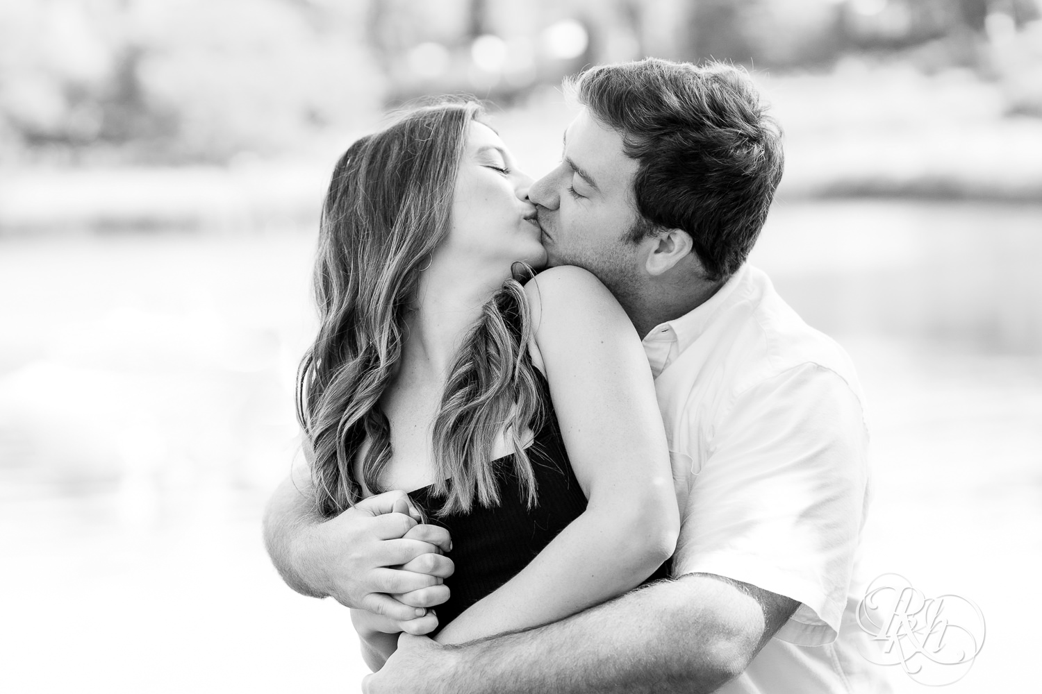 Man and woman kiss during engagement photography at Centennial Lakes Park in Edina, Minnesota.