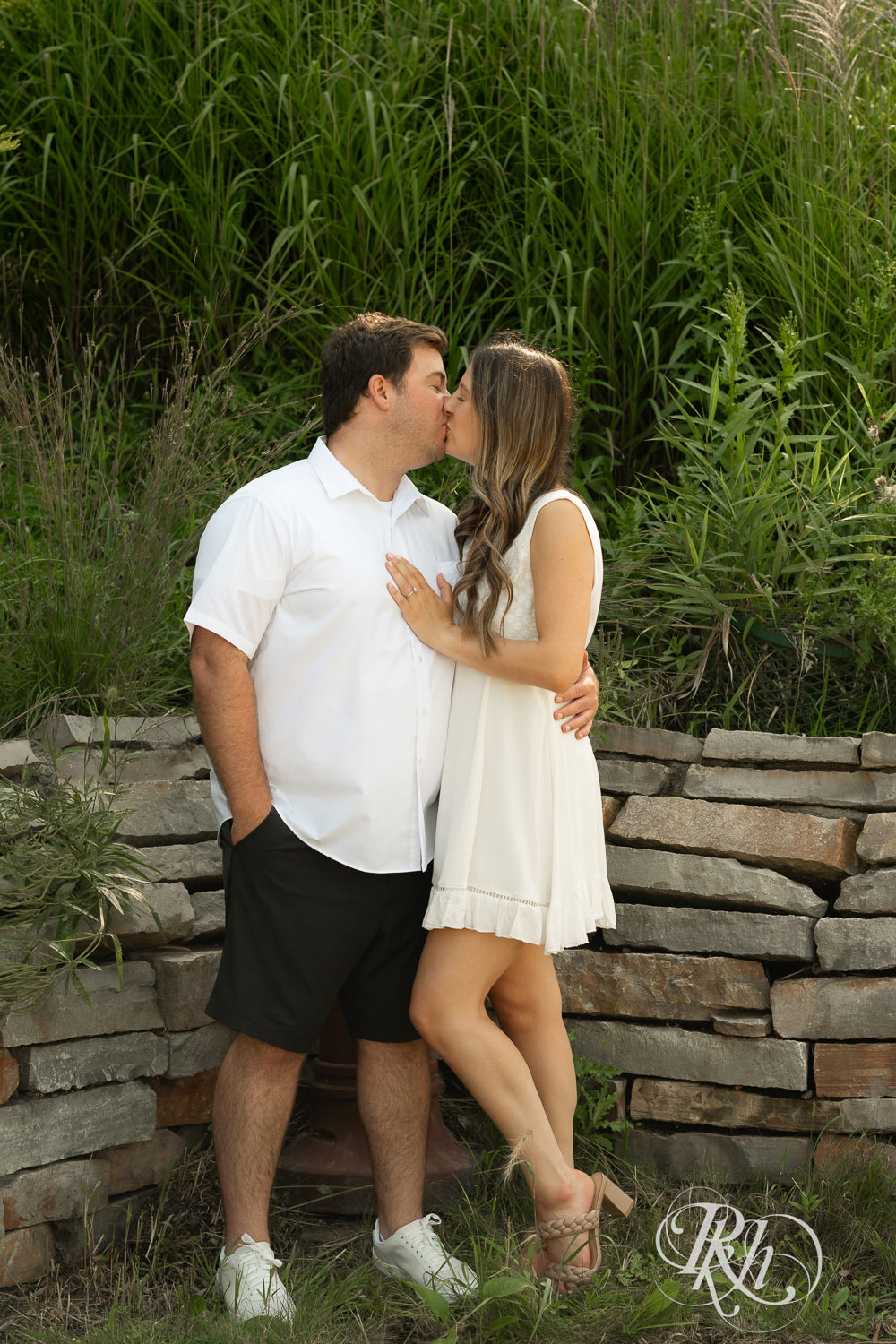 Man and woman in white dress kiss during engagement photography at Centennial Lakes Park in Edina, Minnesota.